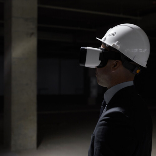 Dark side view portrait of businessman wearing VR gear at construction site while visualizing future project in 3D, copy space